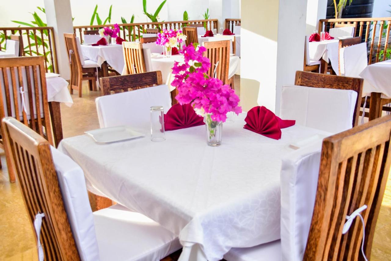 Bright restaurant interior with white linen and fresh bougainvillea on every table